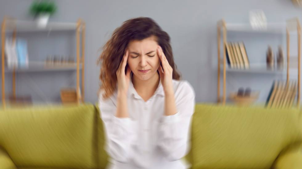 Woman feels dizzy and sits down on the couch.