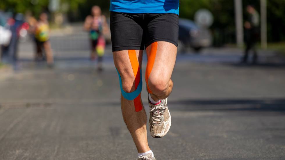 Runner feet in kinesiotape running marathon on road
