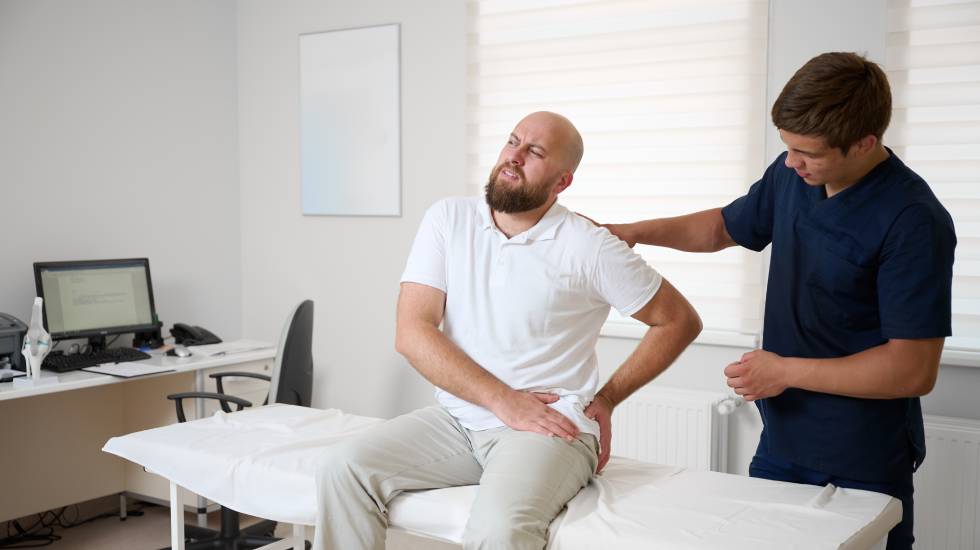 Man suffering from hip pain during medical consultation in physiotherapy clinic.
